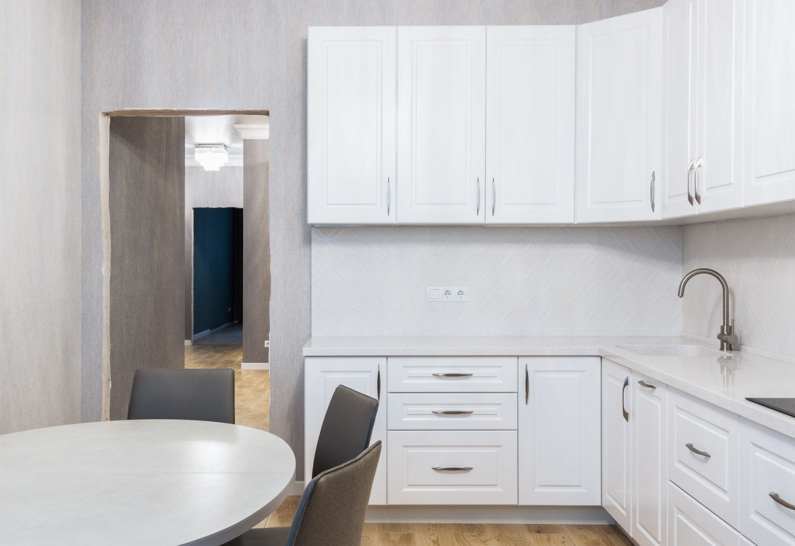 Clean white kitchen with new cupboard doors and a modern tap