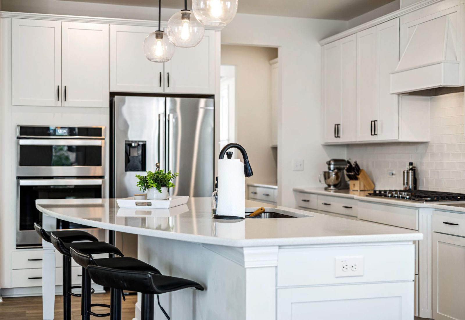 Bright white kitchen with a large island, pendant lighting and stainless steel appliances