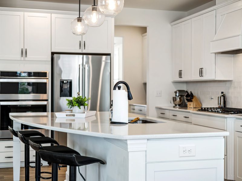 Bright white kitchen with a large island, pendant lighting and stainless steel appliances